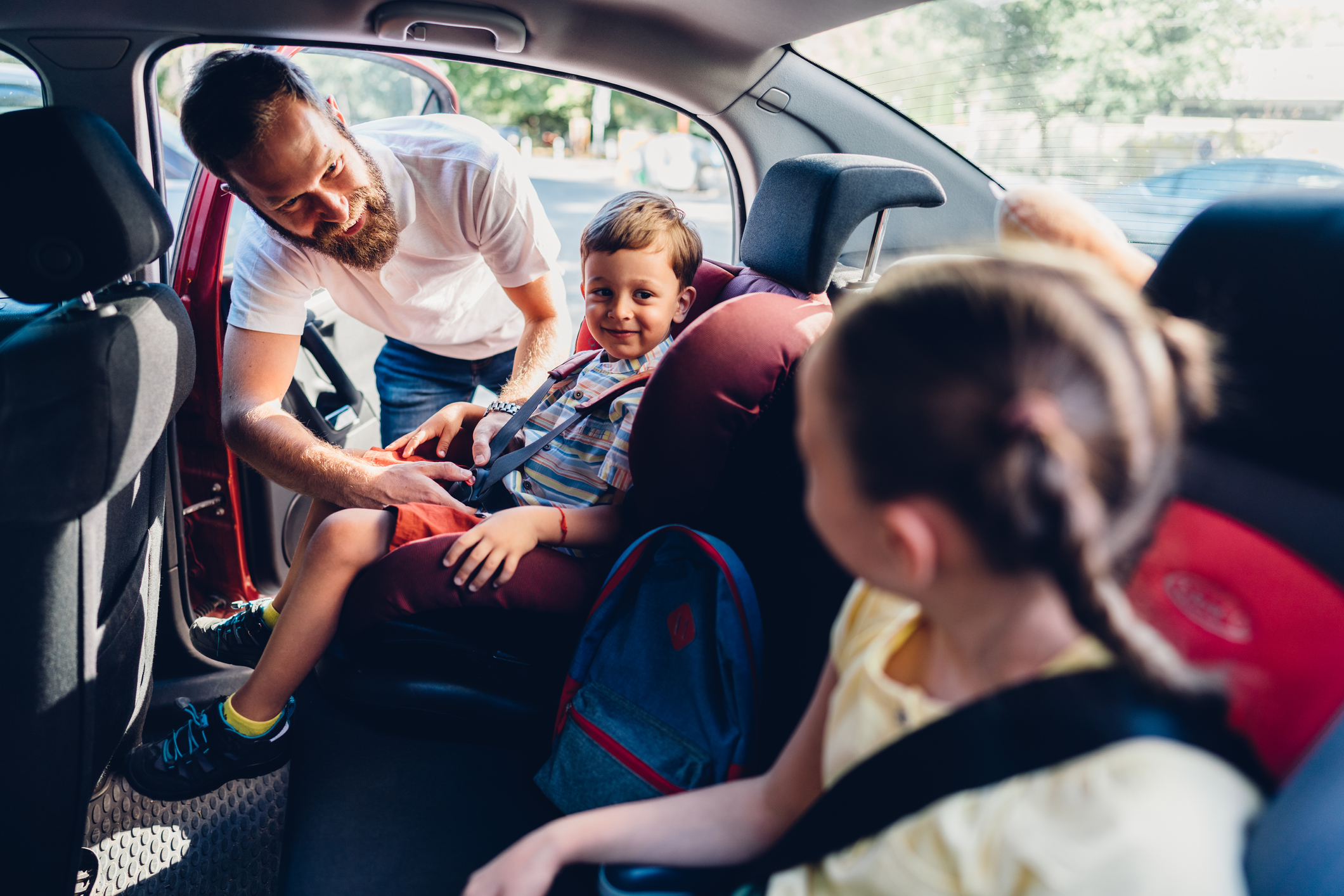 A father placing his children into their car seats.