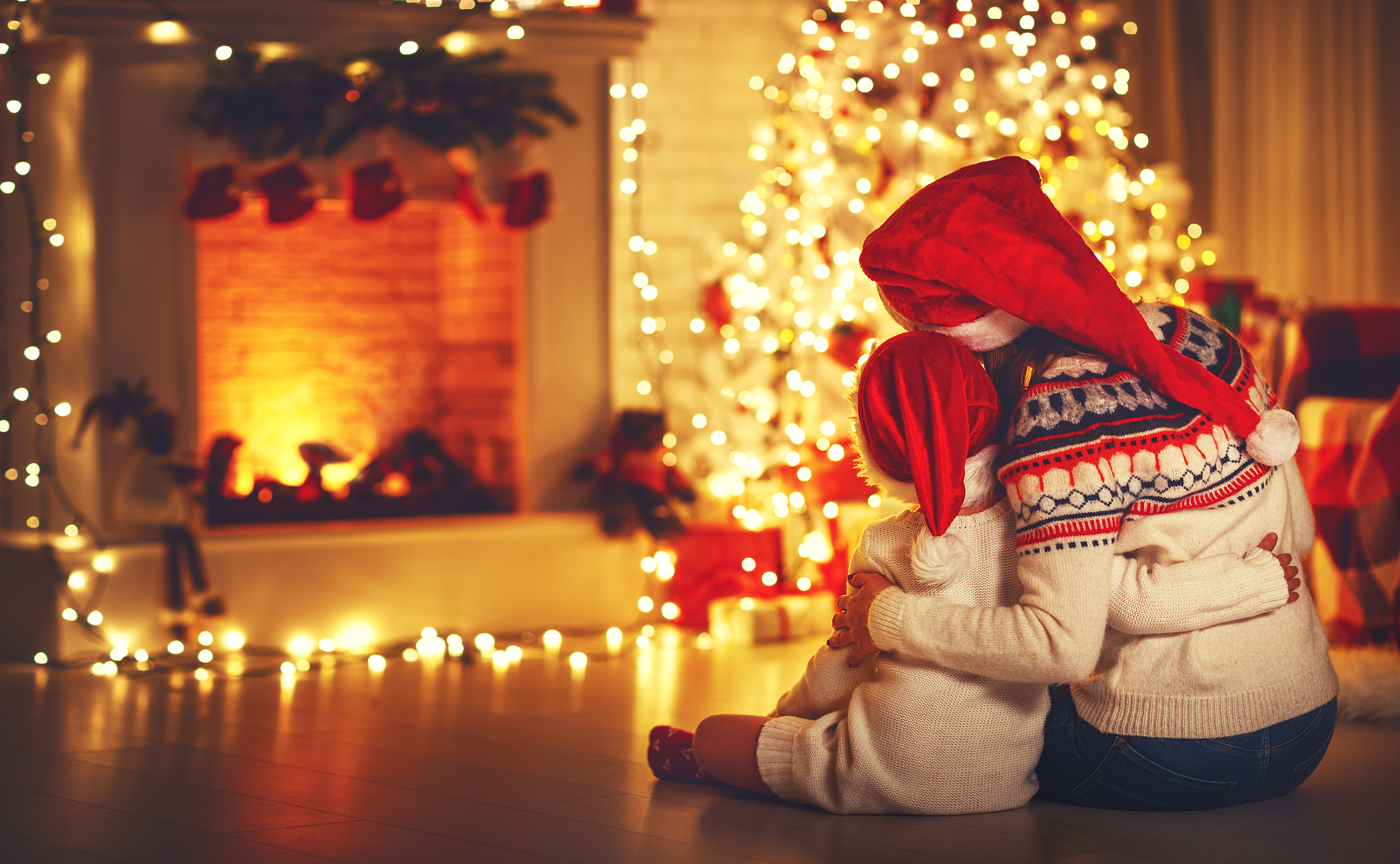 A family admires their Christmas decor by a fireplace.