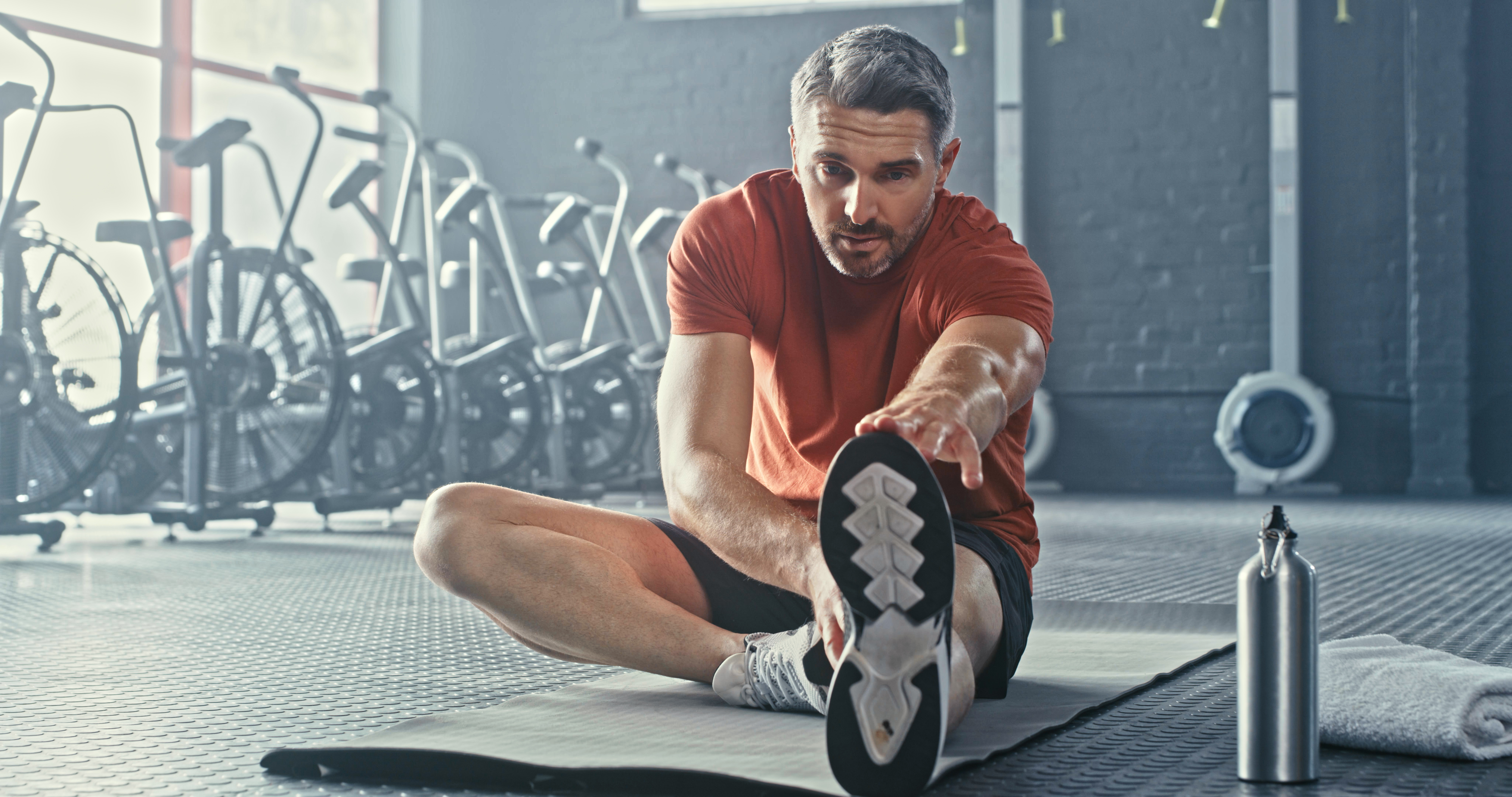 A man stretches prior to using bikes at the gym.