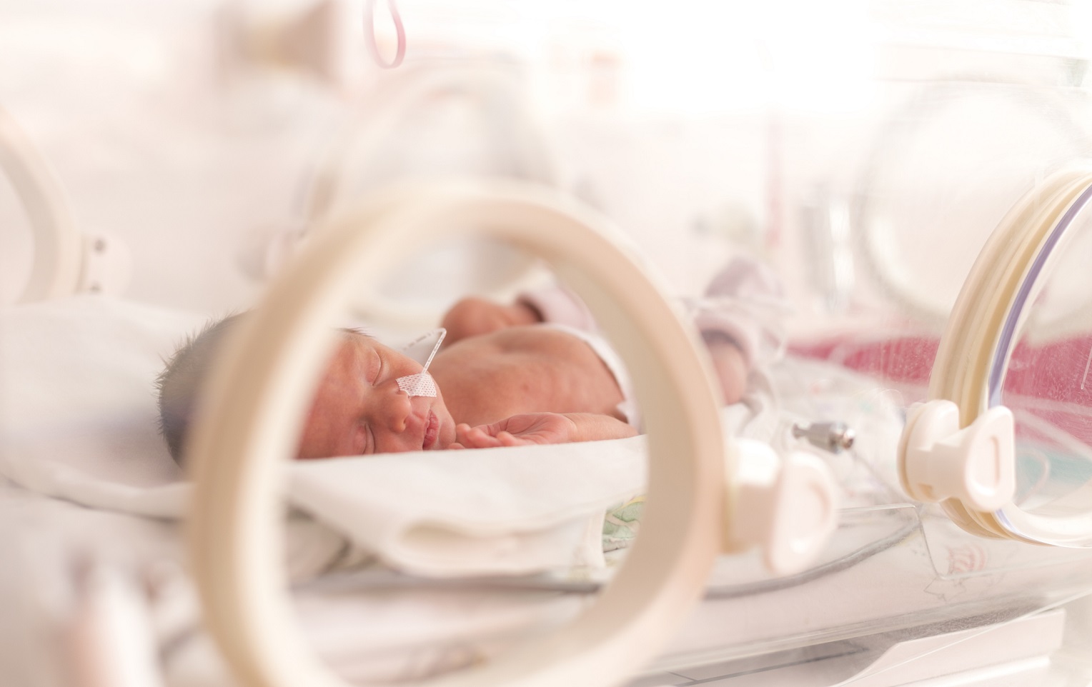 A baby lying in a NICU bed.