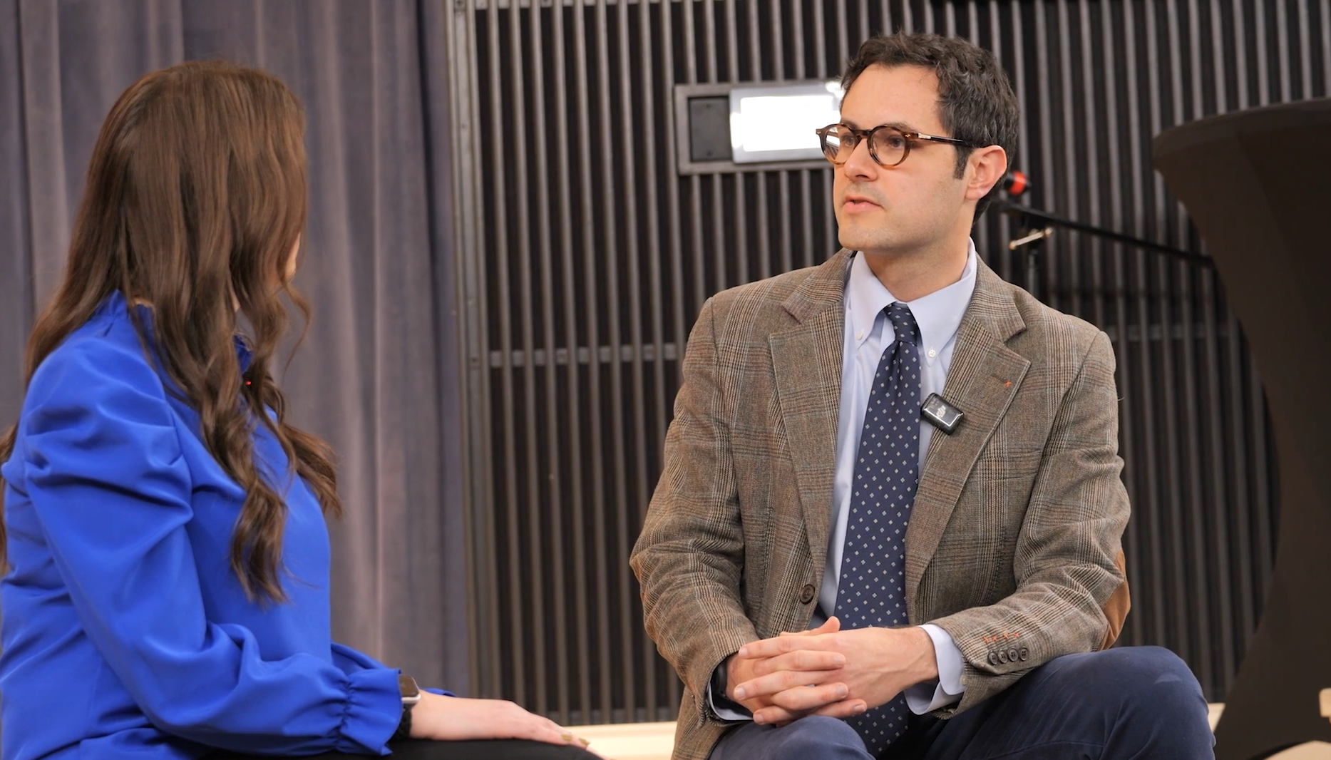 Dr. Neil Toupin, seated on a stage to the right, speaks to Alyssa Abend, a marketing manager for UK HealthCare, who's seated in the frame to the left