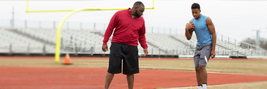 An athletic trainer works with an athlete on a ball field.