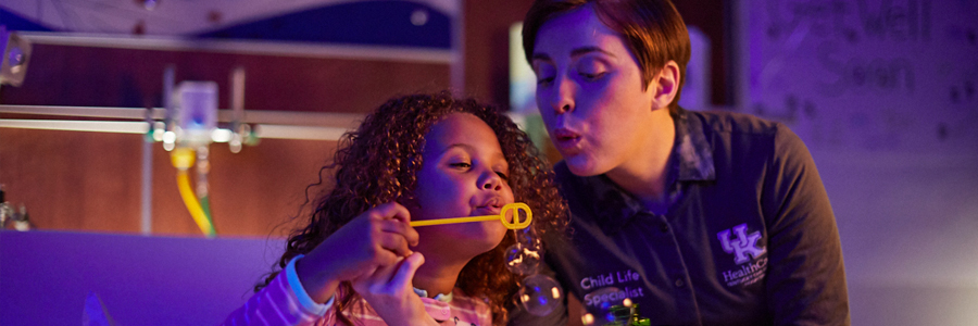 Child Life specialist blows bubbles for patient.