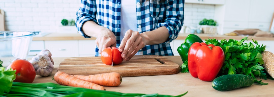 Woman cuts a tomato in her kitchen.