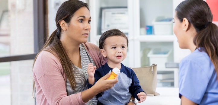 A mother with her toddler on her lap holds a pill bottle