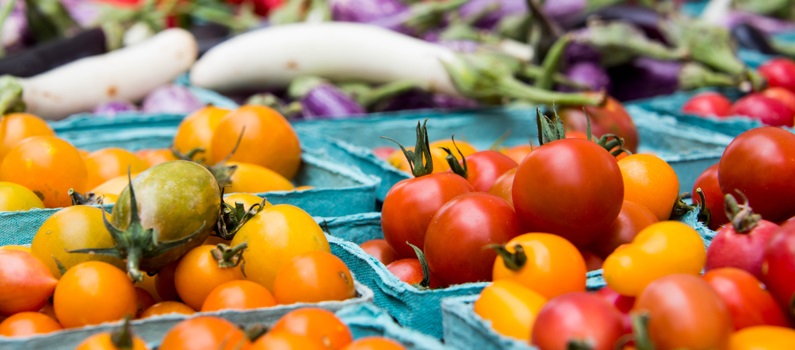 A selection of tomatoes and other vegetables at a farmers market.