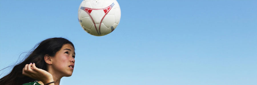 A young girl "heads" a soccer ball.