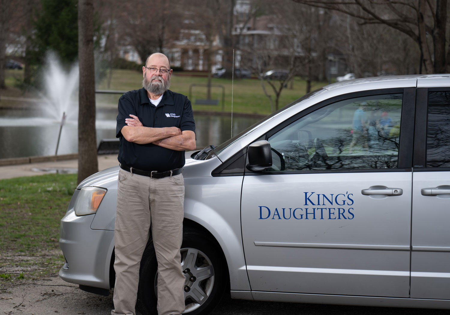 Tom Adams, a transplant recipient, stands in front of a UK King's Daughters transportation van.