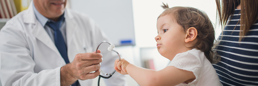 Girl playing with a stethoscope at doctor's office