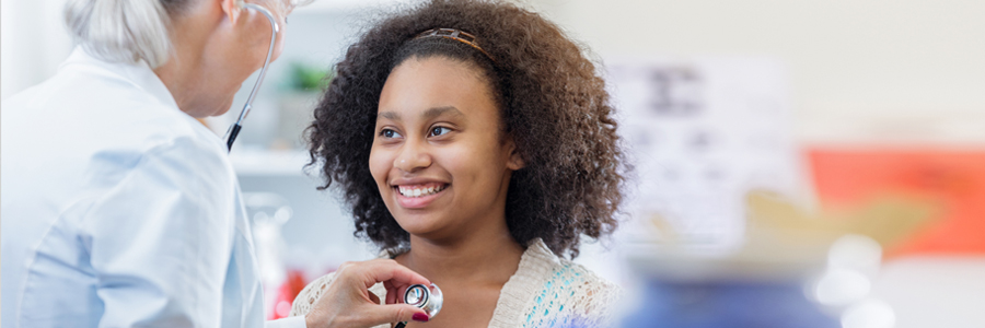 A doctor listens to a teenage girl's heart.