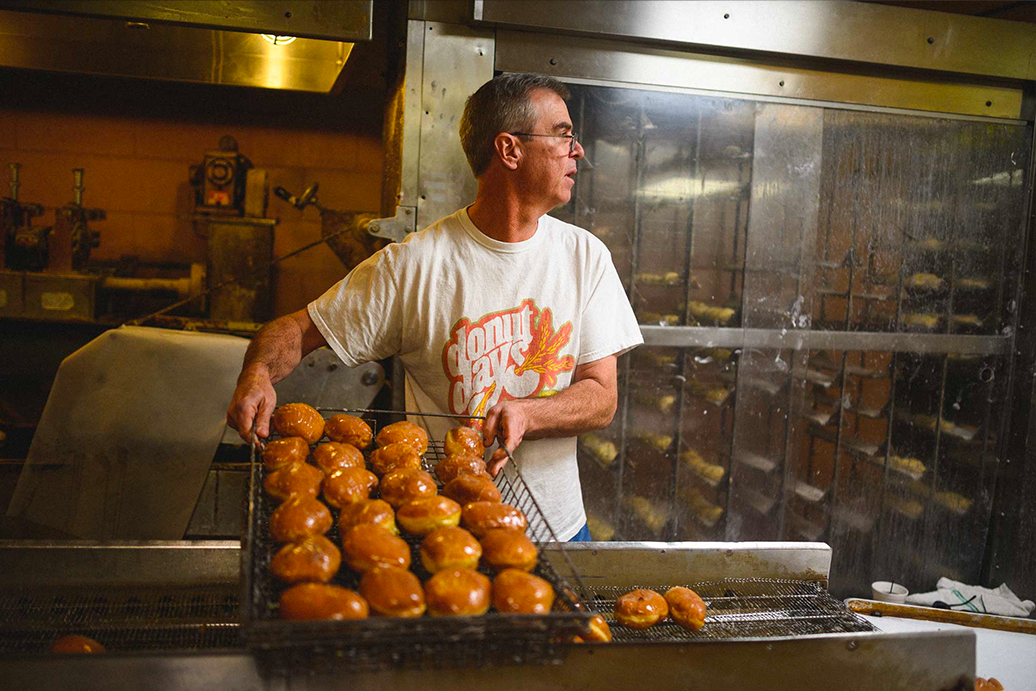 Fred Wohlstein lifts a basket of glazed doughnuts.