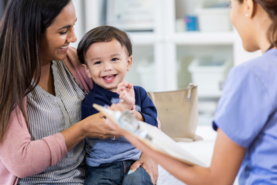 A mother holds her toddler son at the doctor's office.