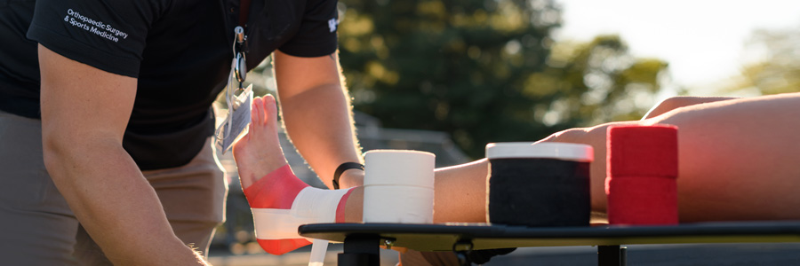 Trainer Cody Begley wraps a soccer player's leg.