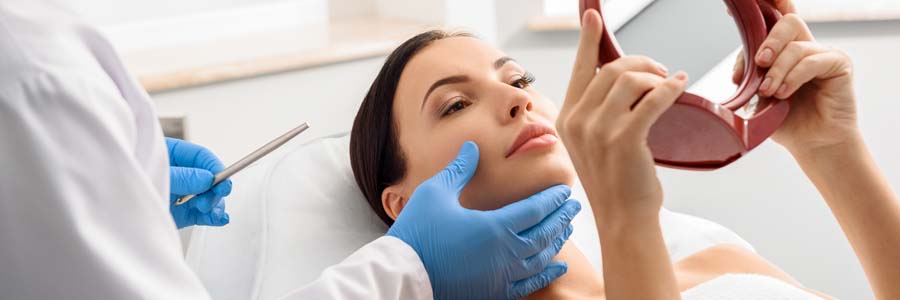 woman looking into mirror at surgery consult