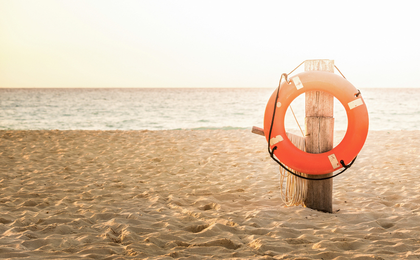 A life preserver hangs from a post on the beach.