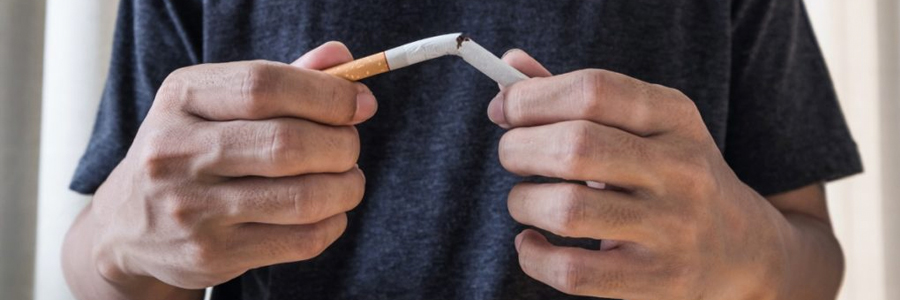 A man breaks a cigarette in half.