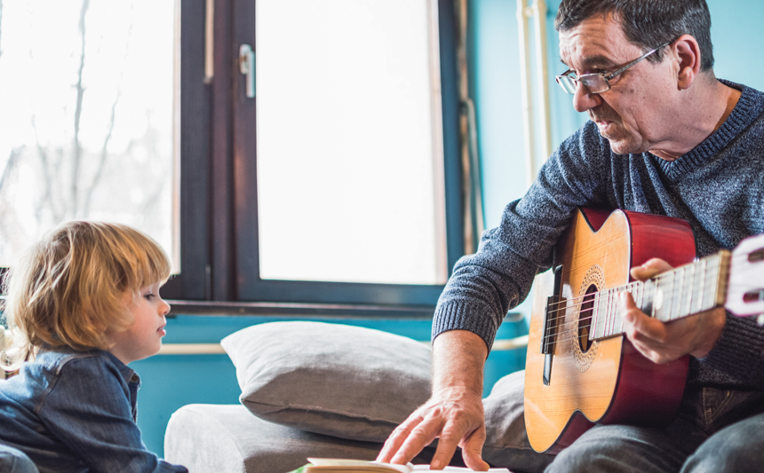 A man plays guitar with a young child.