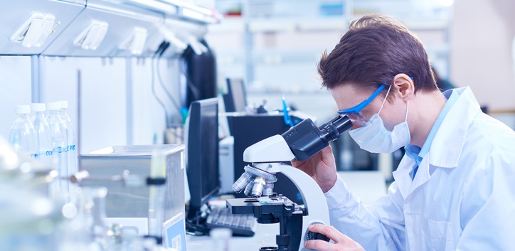 Researcher looks through microscope.