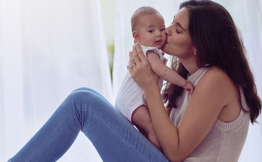 A mother kisses her baby.