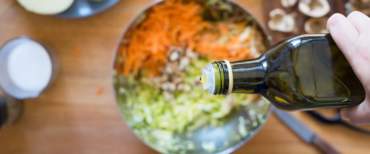 Olive oil is poured over vegetables.