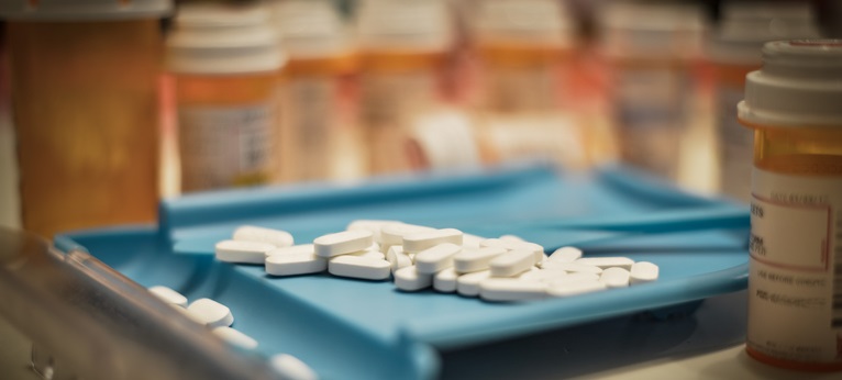 Unsorted prescription pills sit in a pharmacist's counting tray before they are bottled.