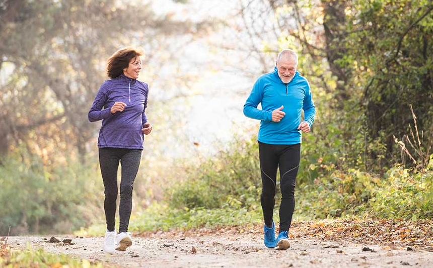 A senior couple jog on a trail.