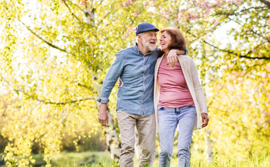 A senior couple walk arm-in-arm outdoors.