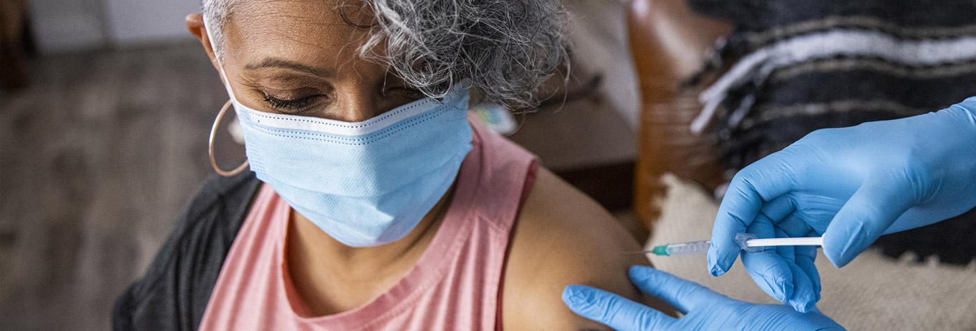 Imagen de una noticia femenina vacunando a una paciente.