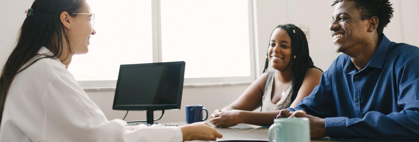 Doctor seated at a desk speaks with an African-American teen and their parent