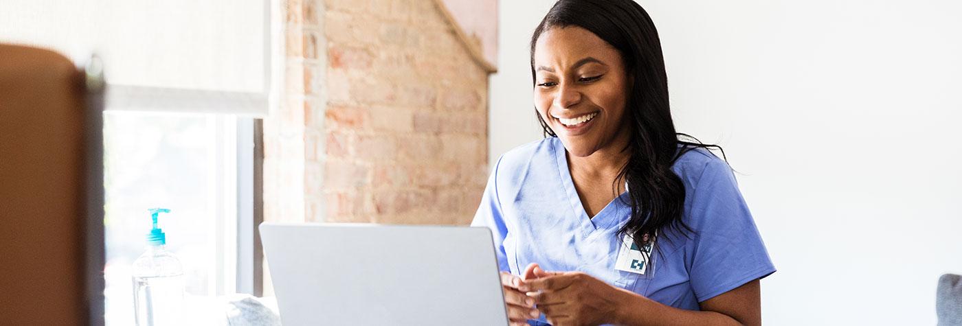 Smiling female doctor participates in a teleconference using her laptop computer