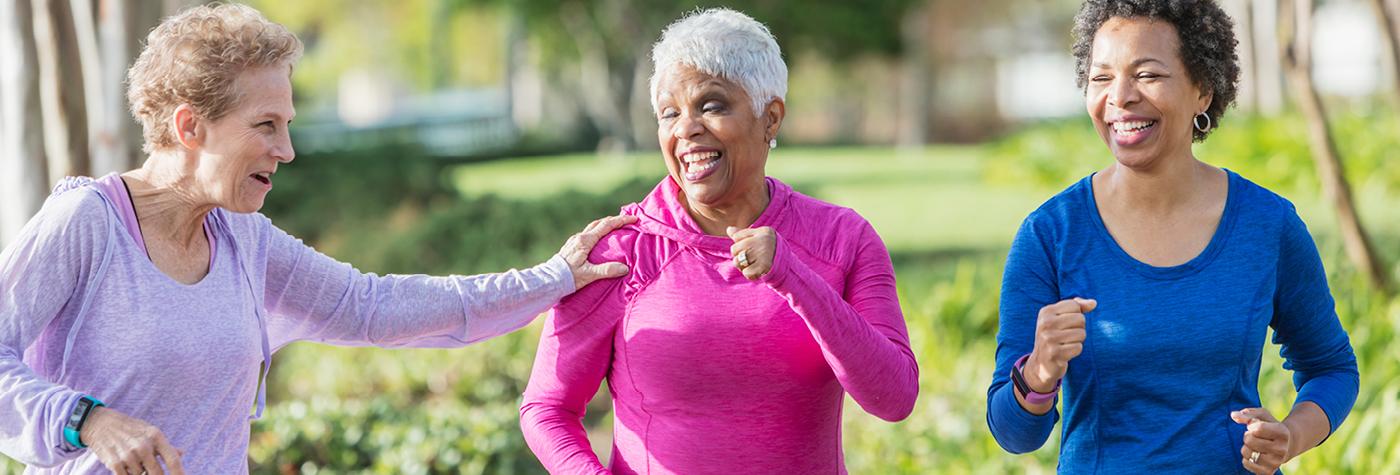 Three women in workout gear walk together outdoors.