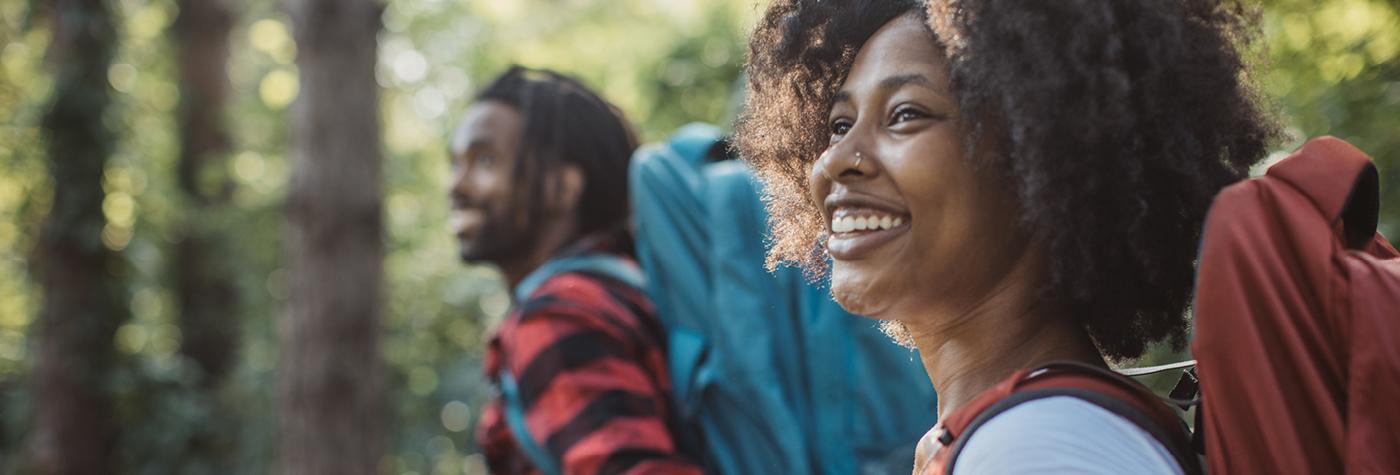 Close-up photo of an African-American man and woman hiking in the woods. 