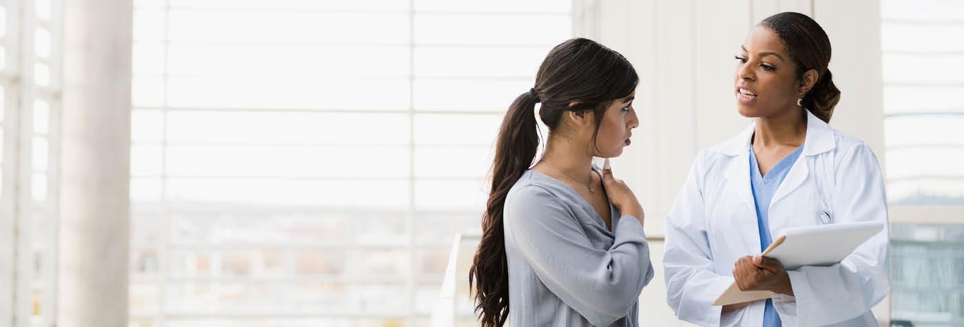 A femal doctor in a white coat has a conversation with a young woman.