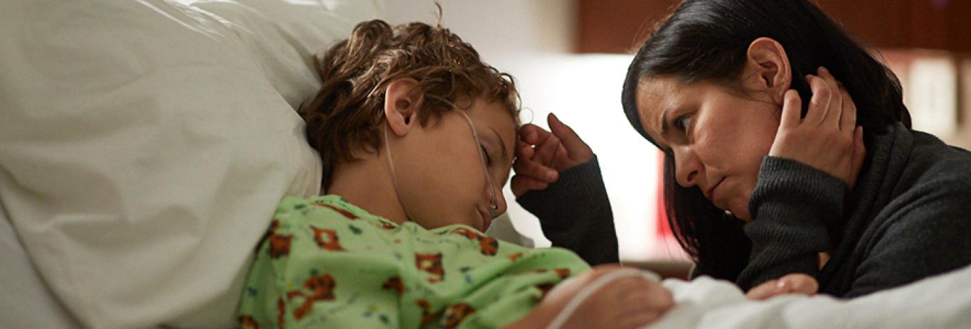 Mother looking over son in hospital bed