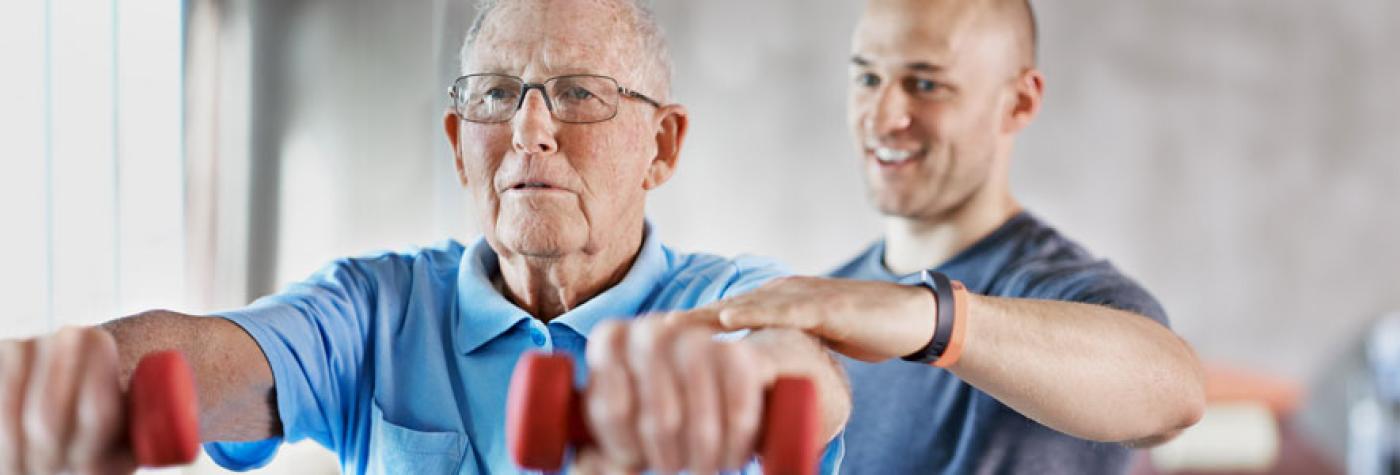 A physical therapist helps a patient using hand weights.