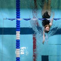 Alayna Benningfield performing a backstroke in a swimming pool, shot from overhead.