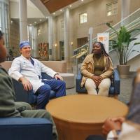 Dr. David Dornbos, a surgeon a UK HealthCare, sits with Tiona Stevenson and her family in a lobby.