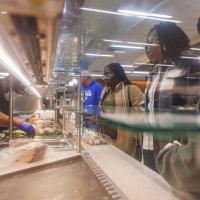 Tiona Stevenson's family observes a cafeteria worker as they select items to eat for lunch.