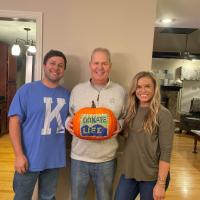 James Fielding stands beside two family members while holding a pumpkin with the Donate Life logo painted on it.