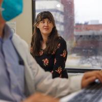 Sarah Custer watches as Dr. Ralph Zinner, out of focus, works on his computer.