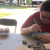 A candid photo of Abby painting a rock in the family’s garage.