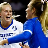 An action shot of Alli and her teammates during a game. Alli is smiling broadly and laughing.