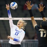 An action shot of Alli during a game, jumping in the air to spike the volleyball.