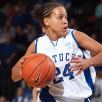 An action shot of Amber during a game, dressed in her game uniform, looking away from the camera while getting ready to pass the ball.