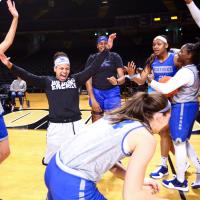 Amber and six of her teammates, all dressed in practice uniforms, celebrate and laugh together on the court.