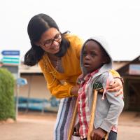 Dr. Shenoi helps a little boy on crutches.