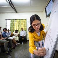 Dr. Shenoi writes on a whiteboard while training with doctors and nurses in Rwanda.