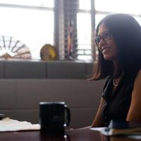 Dr. Shenoi smiles while sitting at her desk.