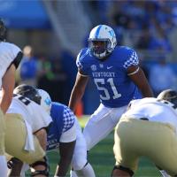 In a photo from his college football days, Courtney stands behind the line of scrimmage, wearing a blue Kentucky jersey with #51 on it.