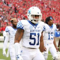 In another photo from his college football days, Courtney walks onto the field with his team. He is wearing a helmet and a white Kentucky jersey with #51 on it.